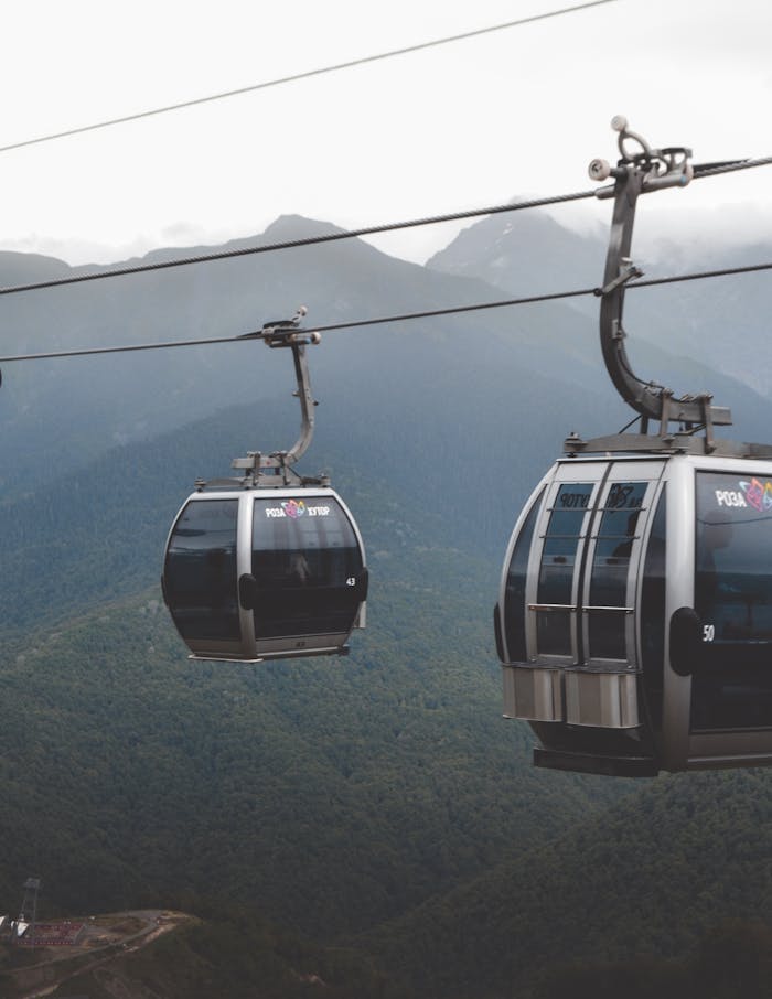 Cable cars traverse lush mountain landscapes in Krasnaya Polyana, Russia, showcasing natural beauty and modern transit.