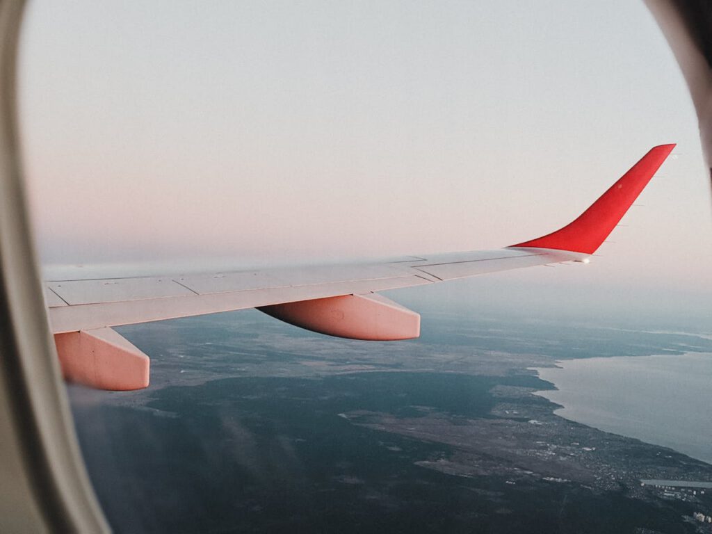 View from airplane window showing landscape of Vienna with sunset sky.