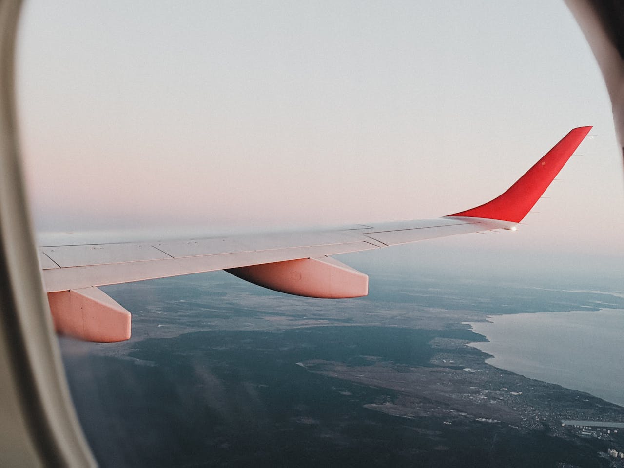why-choose-us View from airplane window showing landscape of Vienna with sunset sky.