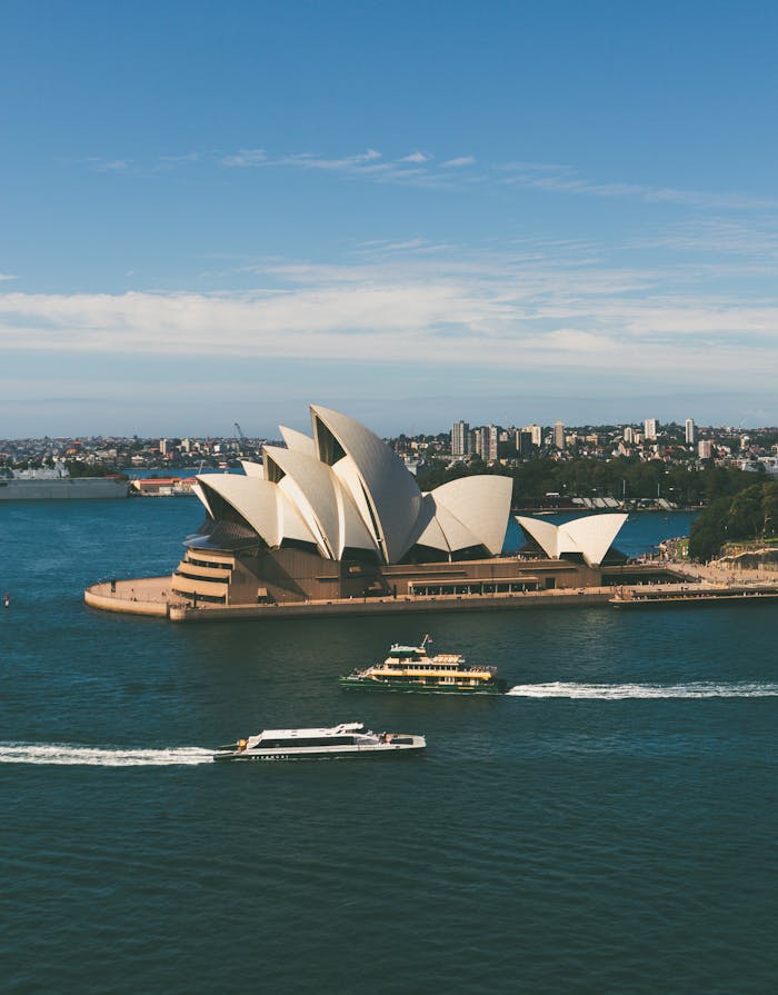 Stunning aerial shot of Sydney Opera House with boats in the harbor on a sunny day.