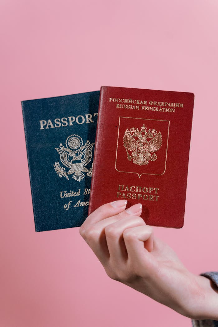 gallery-1 A hand holding US and Russian passports against a pink background.